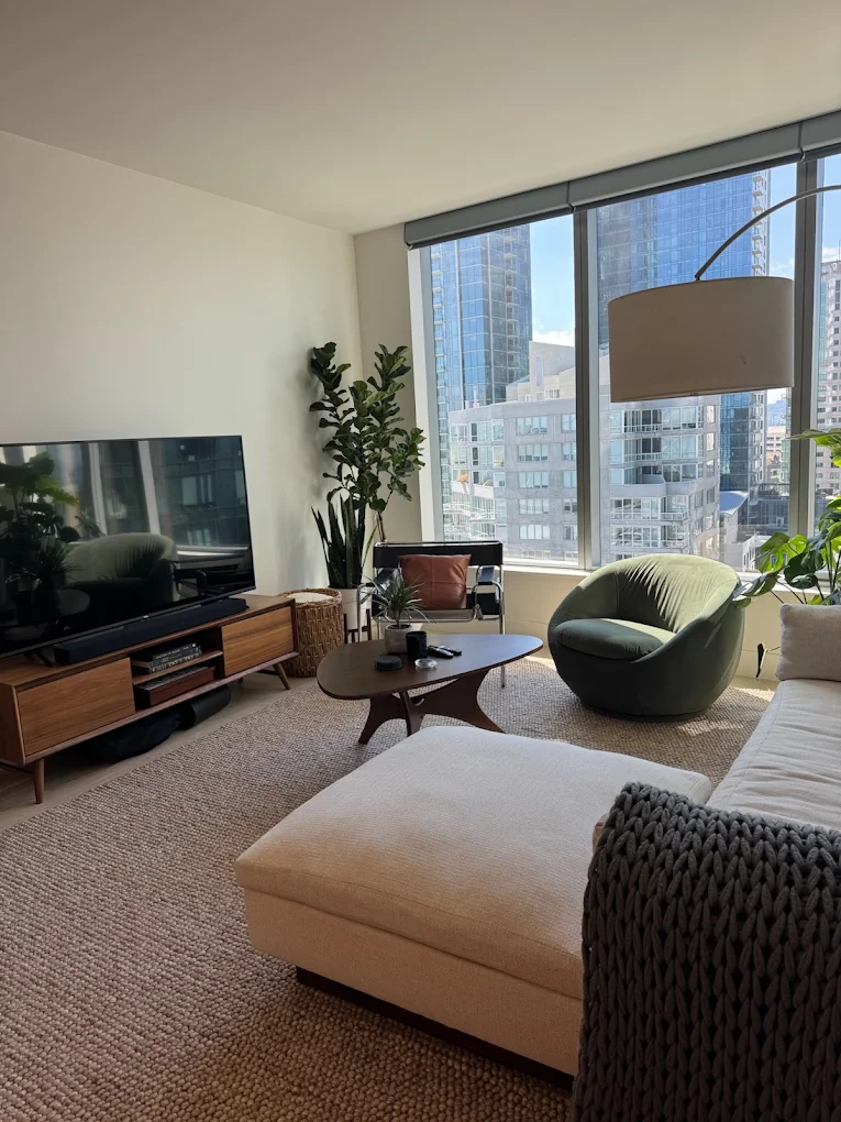 Bright living room with sofa, ottoman and city view