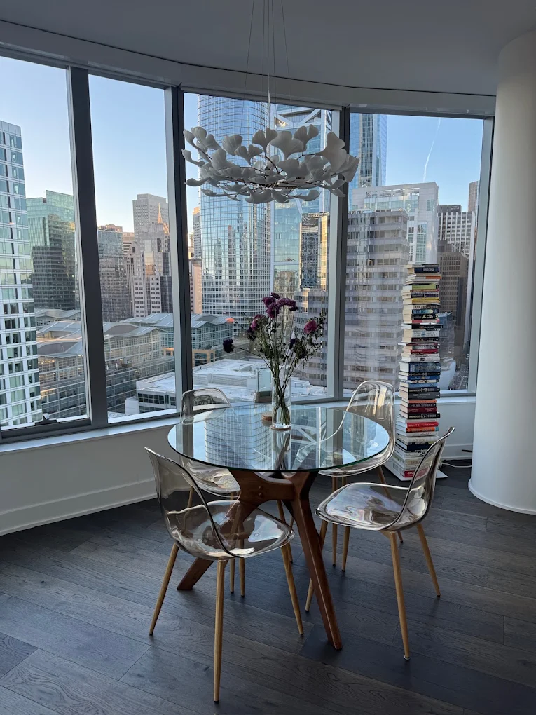 Round glass dining table beside floor-to-ceiling city windows